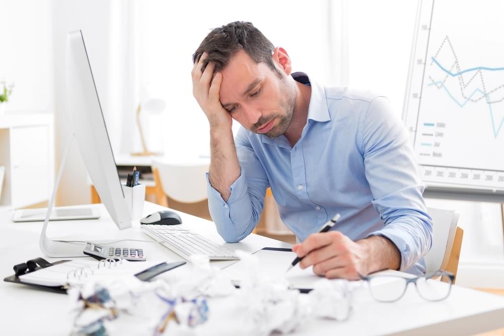 Ondernemer die vermoeid aan zijn bureau zit